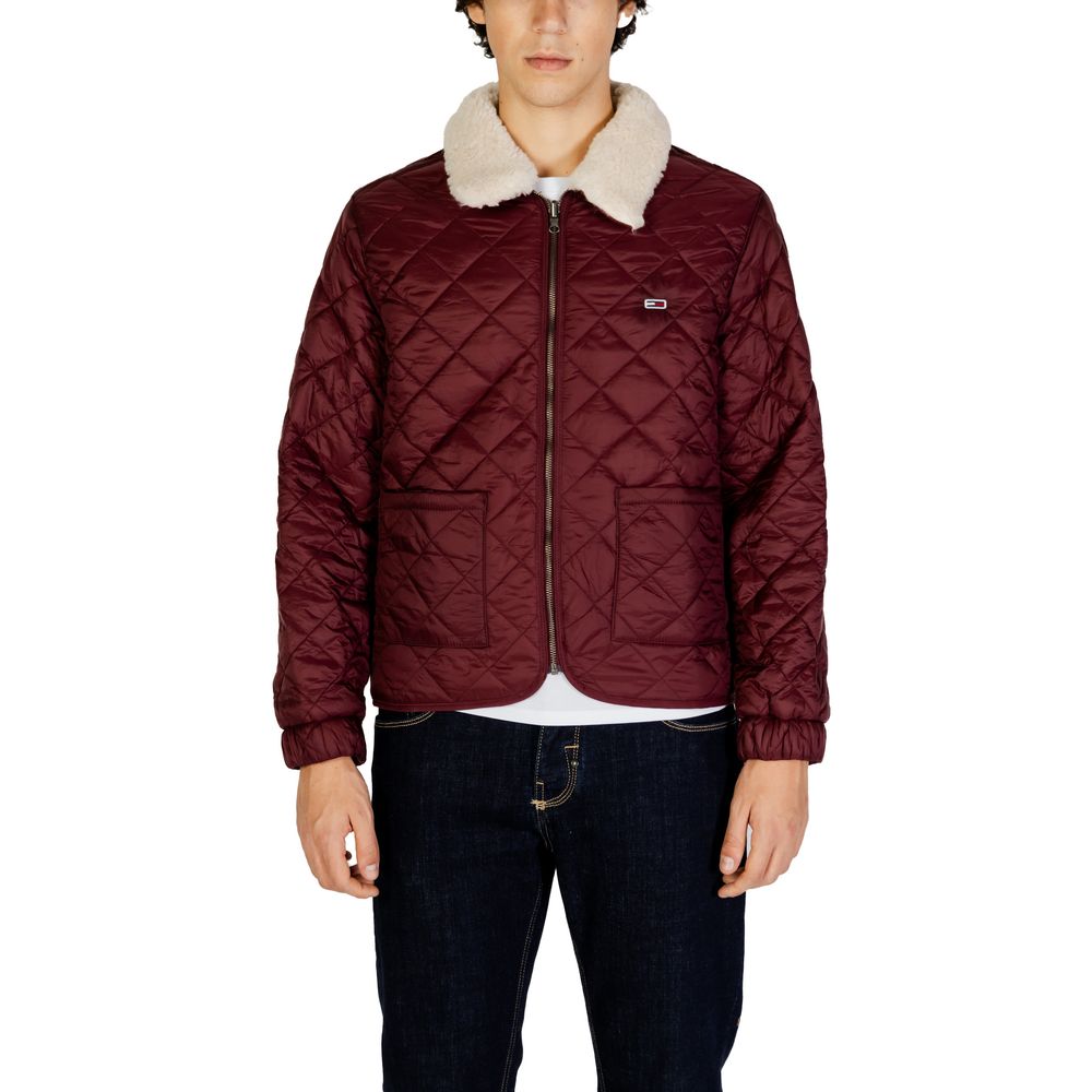 Man wearing a quilted burgundy jacket with a faux fur collar, standing front view