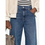 Person wearing Seven Jeans Blue baggy denim with belt loops and five pockets, showcasing whiskering effect at the thighs.