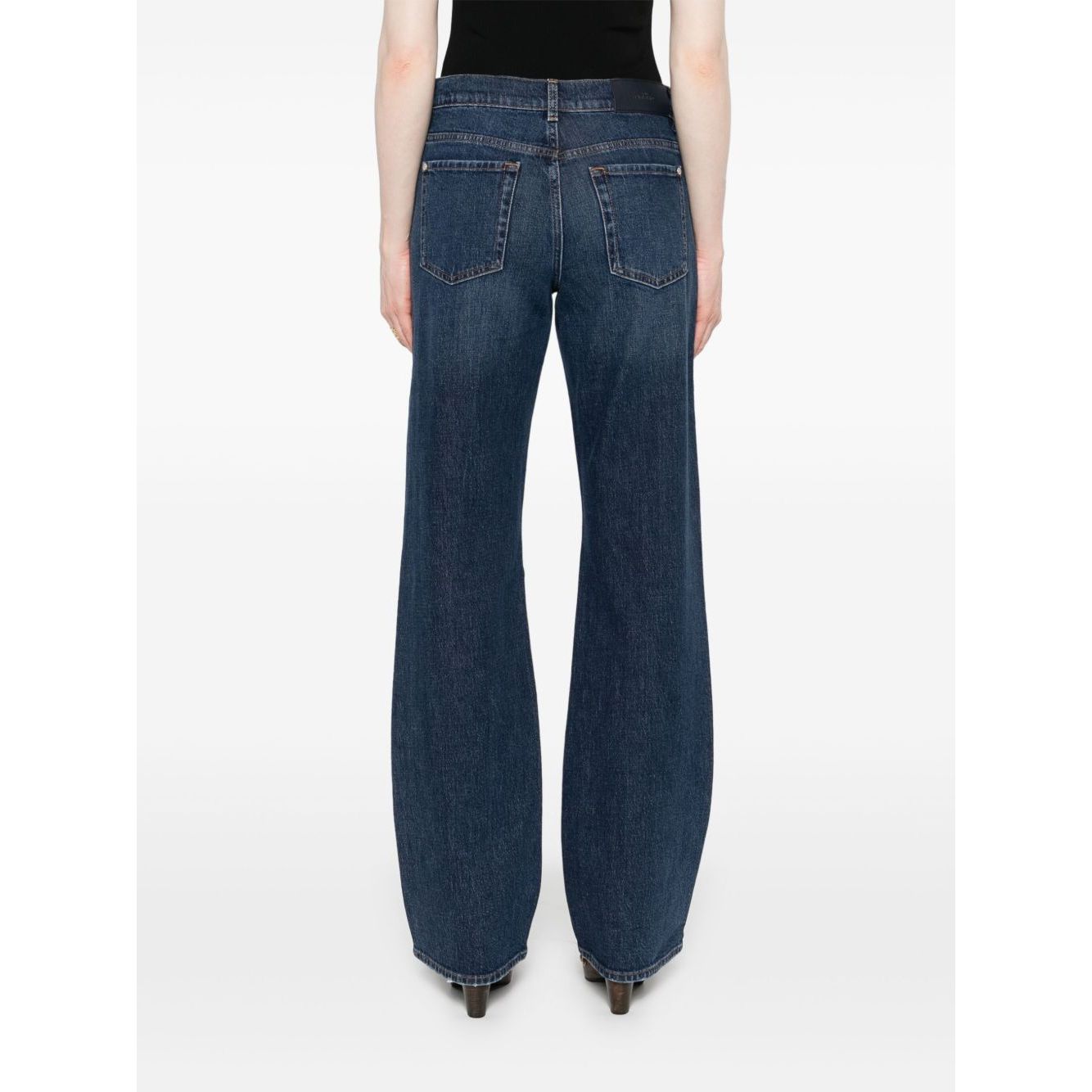 Back view of model wearing navy blue wide-leg Seven Jeans Blue denim with button fly and classic five-pocket design.