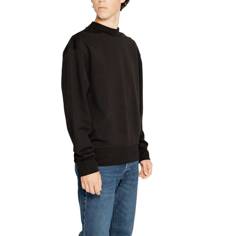 Man wearing Calvin Klein Jeans Black Recycled Cotton Sweatshirt with jeans, highlighting minimalist design and sustainability.