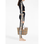 Side view of Burberry Stretch jersey leggings with Check finishes and matching Vintage Check tote bag, featuring check patterns and elastic waistband.