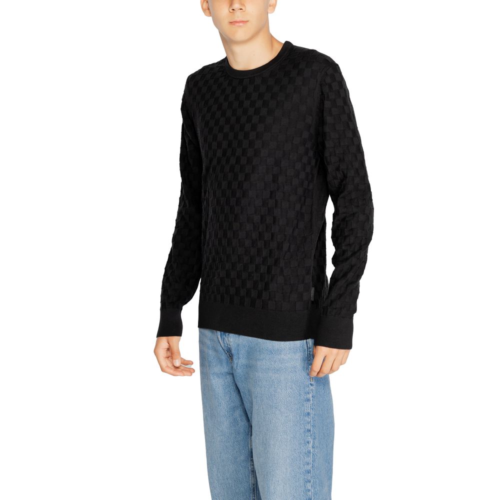 Male model wearing Calvin Klein Black Organic Cotton Sweatshirt with basket weave pattern and crew neck, styled with jeans.
