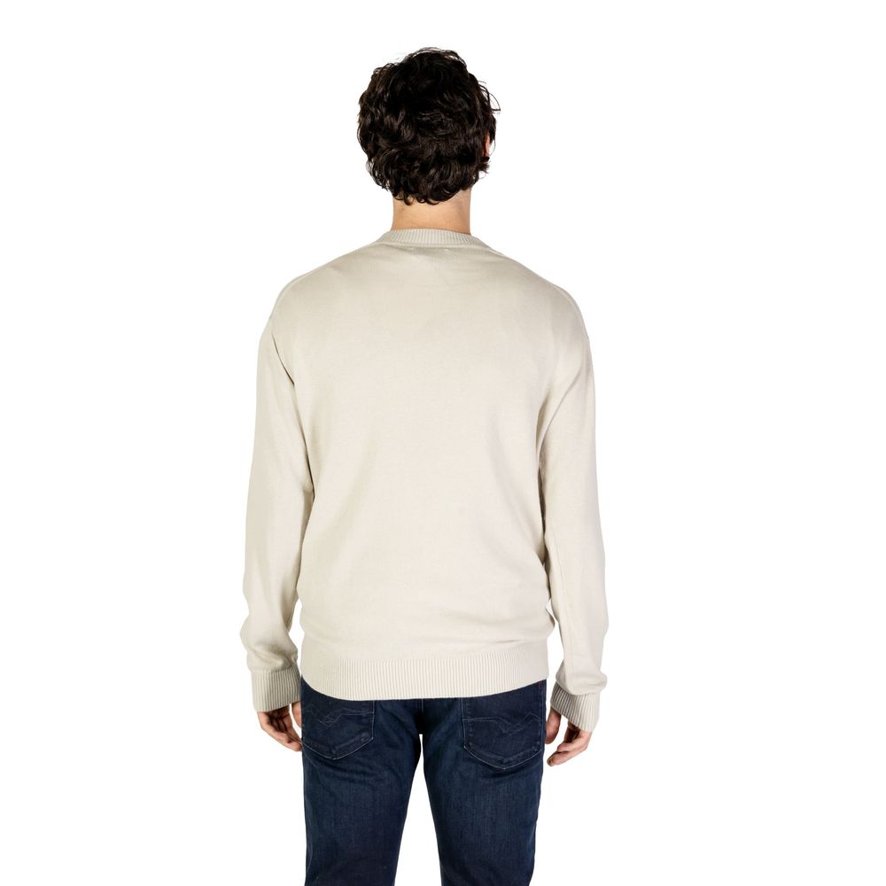Back view of a model wearing a Calvin Klein Jeans Beige Organic Cotton Sweatshirt showcasing minimalist design and CK logo intarsia.
