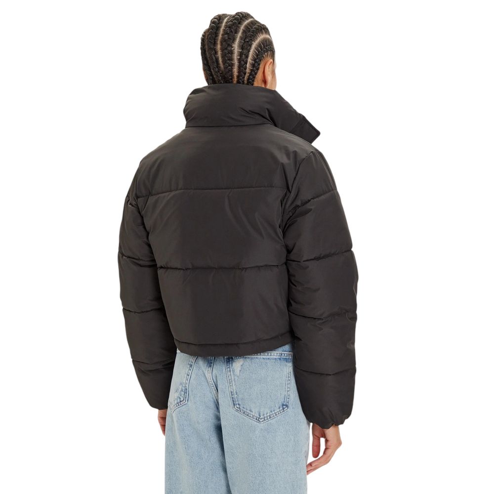 Rear view of a model wearing Calvin Klein Jeans Black Polyester Jackets & Coat, showcasing the cropped puffer style with a high collar.