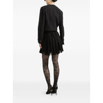 Back view of model wearing Dolce & Gabbana Rachel Tweed Jacket, black crew neck, buttoned cuffs, with a pleated skirt and patterned tights.