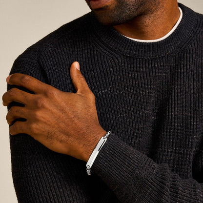 Man wearing FOSSIL JEWELS JEWELRY Mod. JF04767040 bracelet, close-up on wrist against black sweater background.