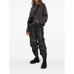 Model wearing GANNI Boots Black with chunky rubber soles, slip-on style, and elasticated side panels, paired with grey sweater and black pants.
