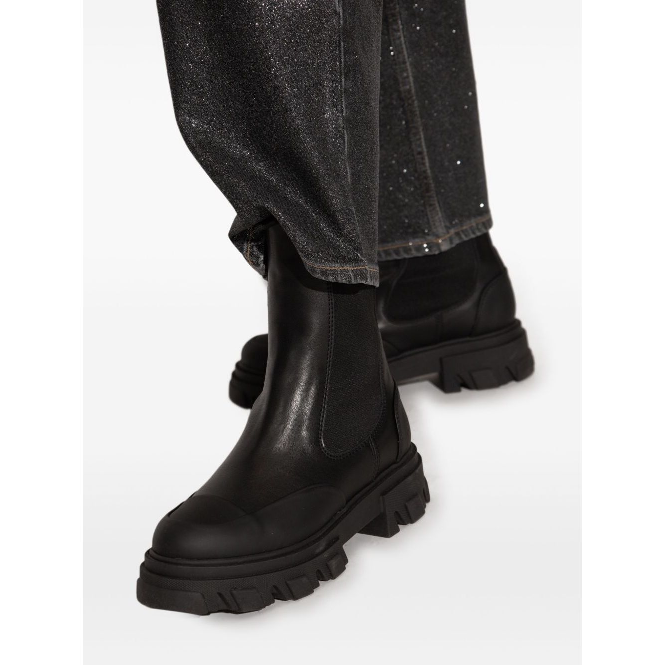 Alt Tag: Person wearing GANNI Boots Black with chunky rubber sole and elasticated side panels, showcasing slip-on style and Chelsea design.