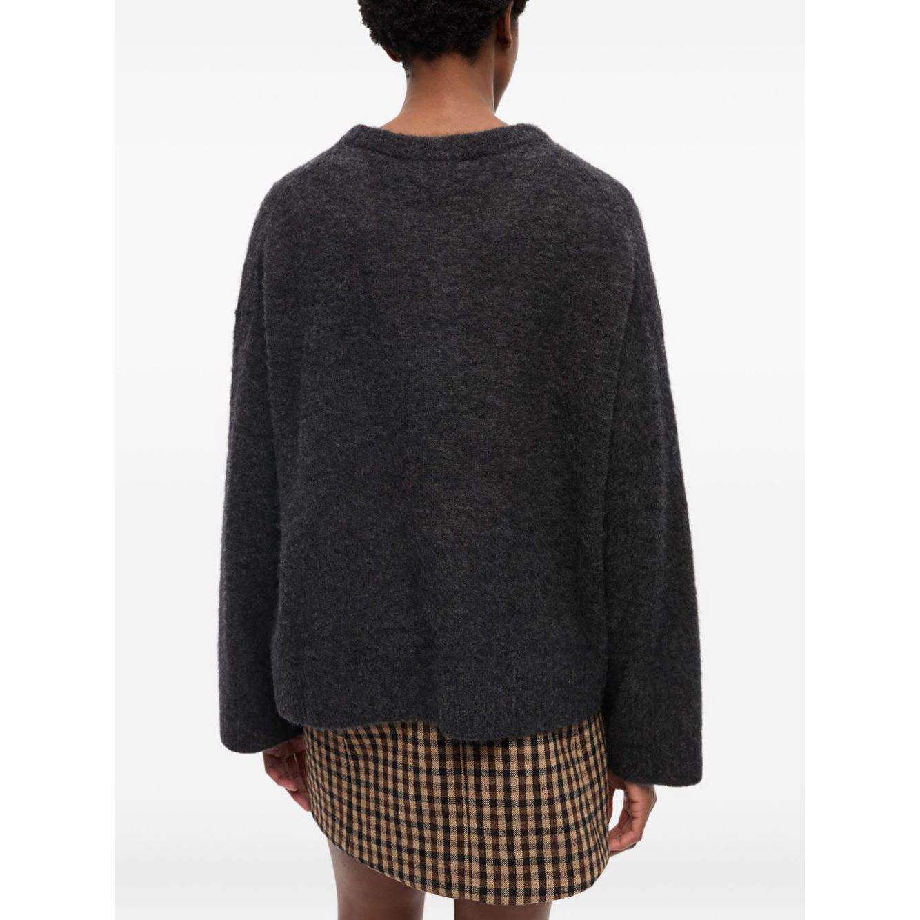 Back view of GANNI Sweaters Grey with long sleeves and ribbed hem, worn with a plaid skirt.