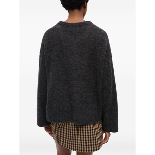 Back view of GANNI Sweaters Grey with long sleeves and ribbed hem, worn with a plaid skirt.