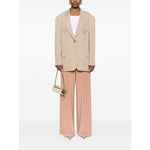 Model wearing Norma Kamali Trousers Beige with elasticated waistband, wide leg, and high-waist design, paired with beige blazer and small purse.