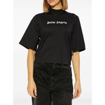 Woman wearing Palm Angels crop T-shirt with logo, black crew neck, drop shoulders, short sleeves, straight hem, size S, standing view.