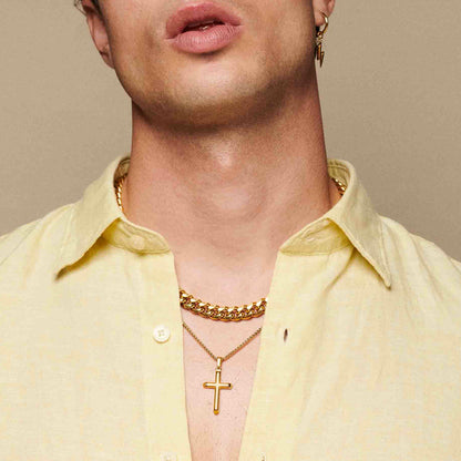 Man wearing gold chain and cross necklace with open yellow shirt on beige background