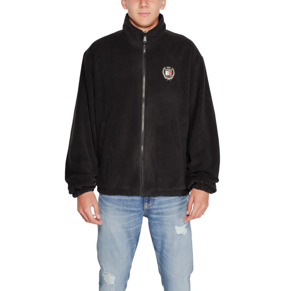 Man wearing Tommy Hilfiger Jeans Black Recycled Polyester Shell Jacket with high collar and embroidered crest.