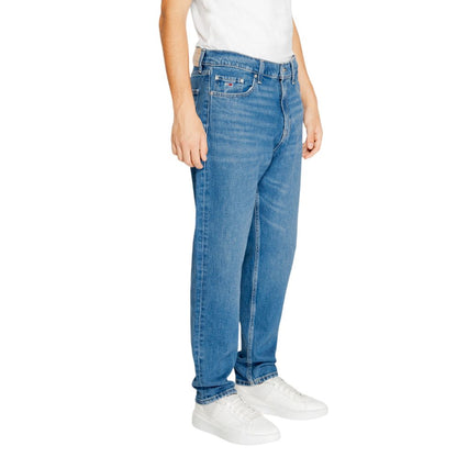 Tommy Hilfiger Jeans Blue Recycled Cotton Slim Fit Jeans on person with white sneakers, showcasing tapered fit and sustainable design.