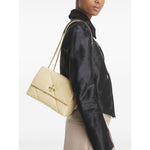 Light yellow Tory Burch Kira Diamond small leather shoulder bag with gold-tone chain-link strap and logo plaque, worn crossbody.