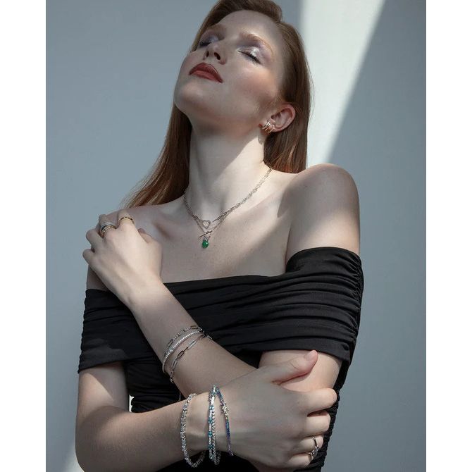 Woman wearing elegant jewelry, bracelets, and necklace in off-shoulder black dress.