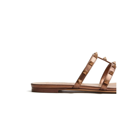 Valentino Garavani Rockstud Low Slide Sandal in Laminated Nappa Leather, brown with signature Rockstud embellishment and flat sole.