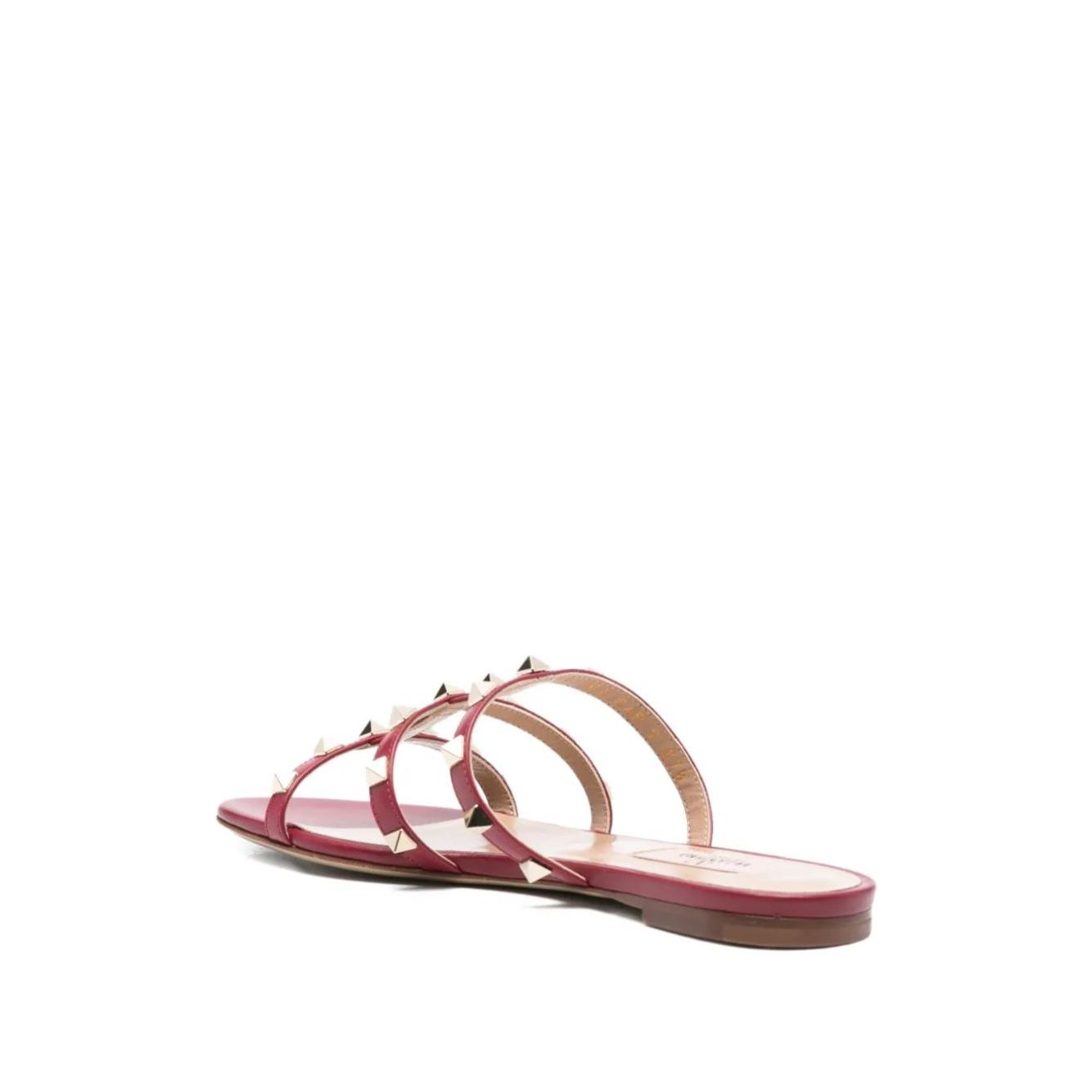 Valentino Garavani Rockstud three-strap sandals in red calf leather with flat sole and stud embellishments, open toe design, heel 1 cm.
