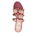 Red Valentino Garavani Rockstud three-strap sandals with open toe and flat sole detailing.
