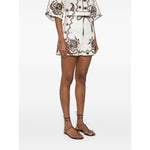 Zimmermann Ascension Shorts in light beige linen with scallop edge embroidery and detachable belt, modeled outdoors.