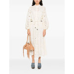 Woman wearing Zimmermann Shirts Ivory blouse with floral detailing, long sleeves, and elasticated cuffs, holding a brown fringe bag.